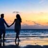Man and Woman Holding Hands Walking on Seashore During Sunlight